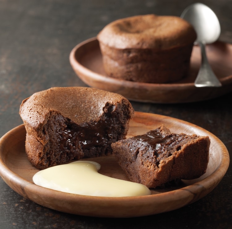 fondant au chocolat au premier plan dcoup en deux avec de la crme anglaise, au deuxime plan: un fondant au chocolat entier