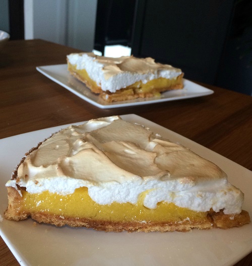 deux parts de tarte au citron meringuée, une au premier plan de profile, l'autre de face