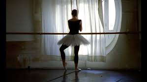 Danseuse en tutu de dos, face à une fenêtre à l'Opéra de Paris.; La photo est légèrement sombre